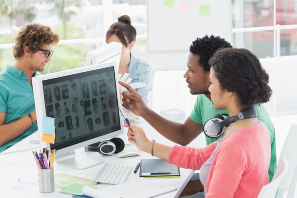 Group of casual young men and women working on computers in a bright office